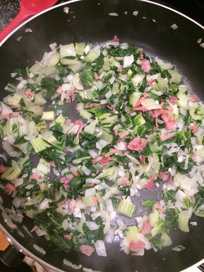 Skillet of garlic, onions, prosciutto, and bok choy.